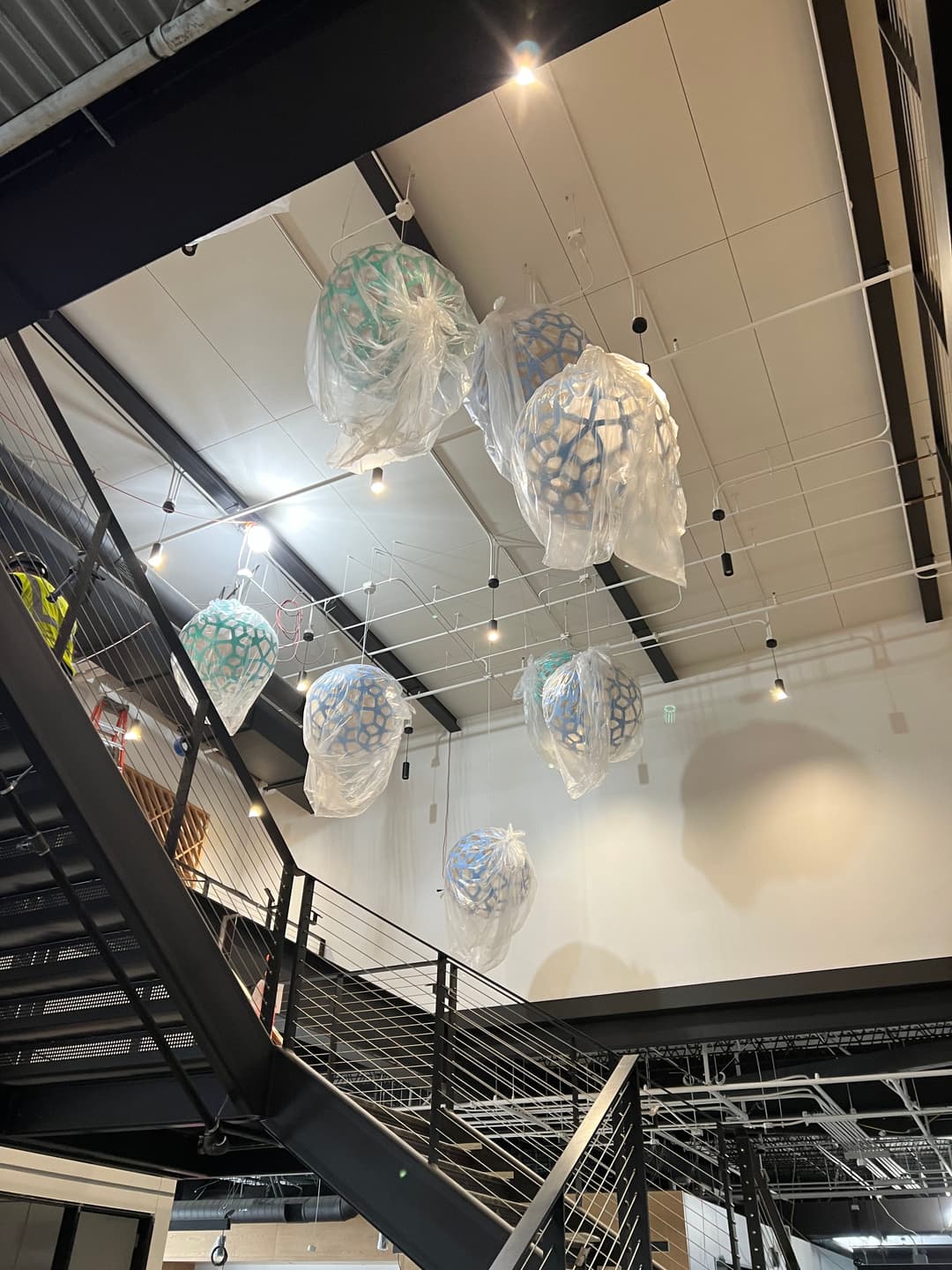 Colorful, translucent light fixtures hanging from the ceiling in a modern interior space.