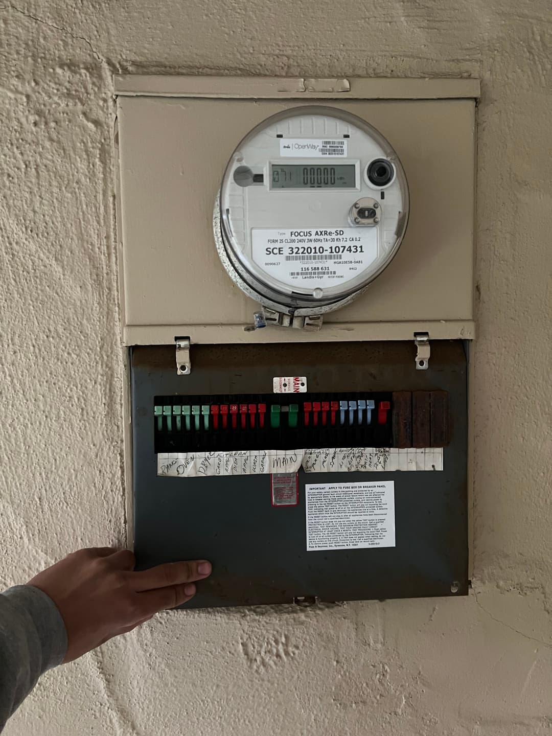 Electric meter and circuit breaker panel with a hand adjusting settings.