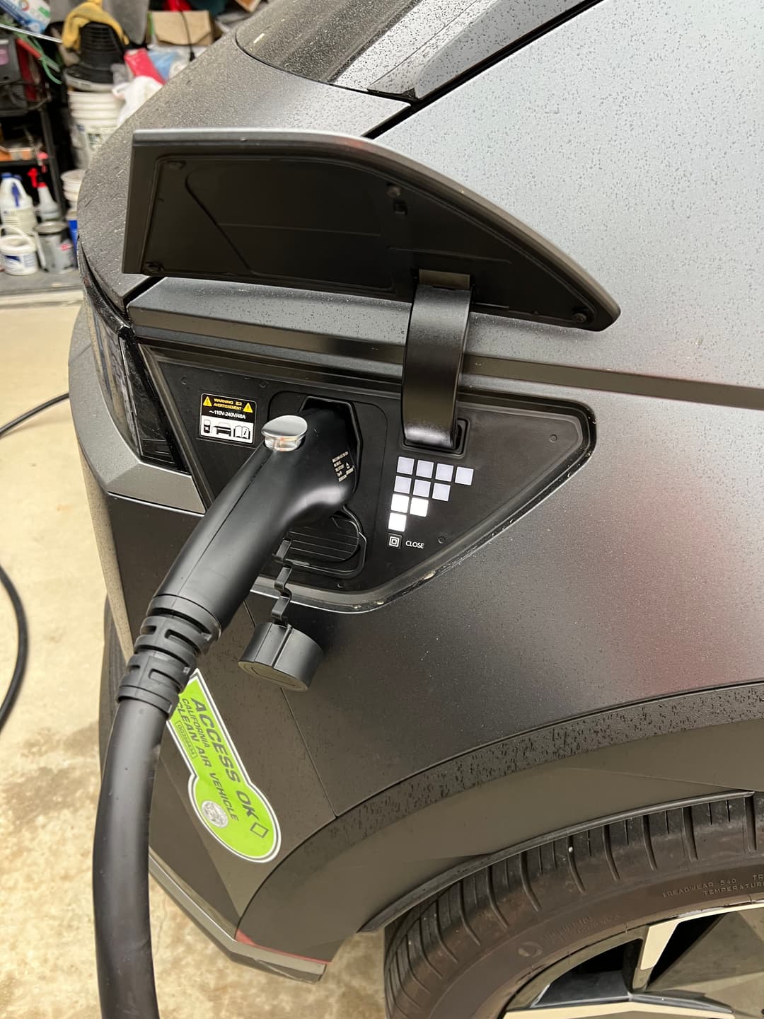 Electric vehicle charging port with connector plugged in, showcasing a modern car's charging setup.