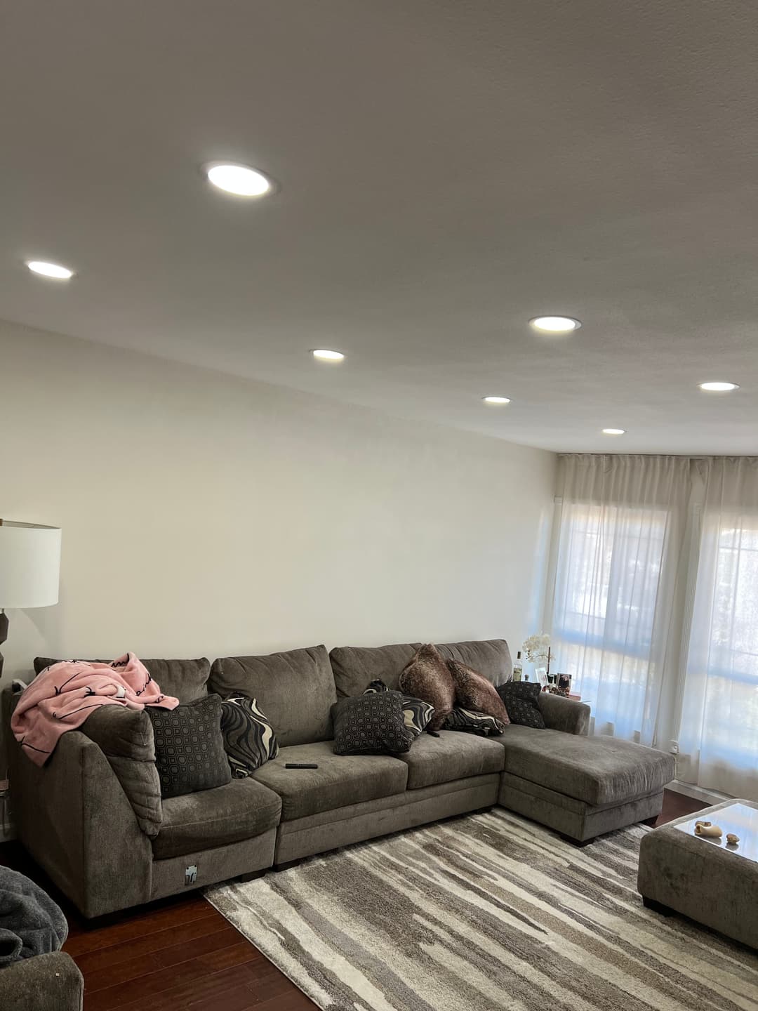 Cozy living room with sectional sofa, decorative pillows, and bright recessed lighting.