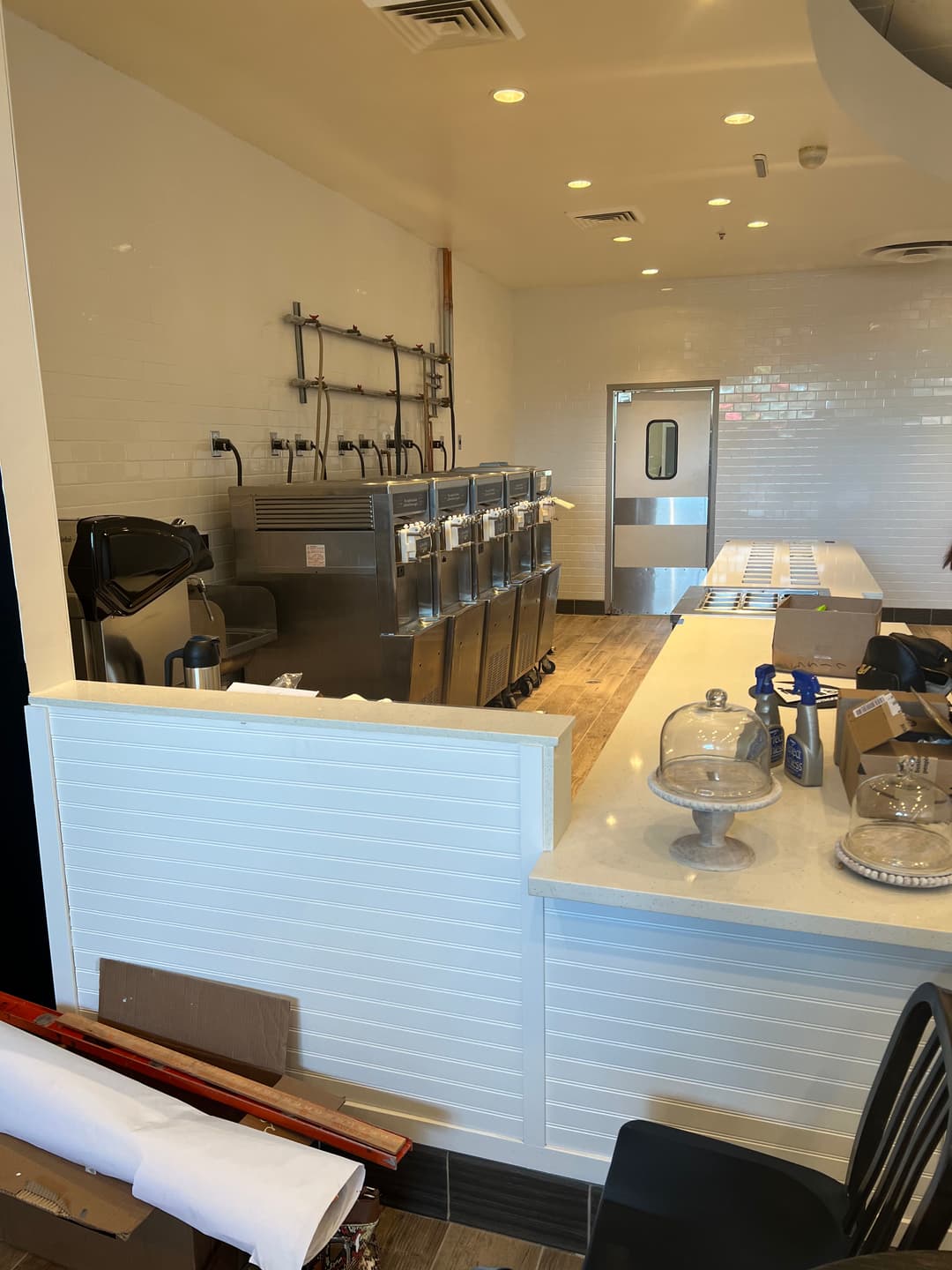 Interior of a cafe featuring a counter, ice cream machines, and preparation area.