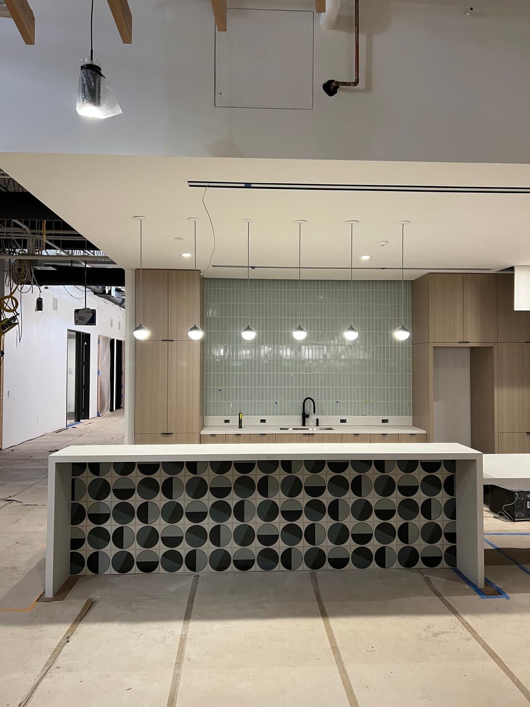 Modern kitchen design featuring a patterned island, pendant lights, and green backsplash.