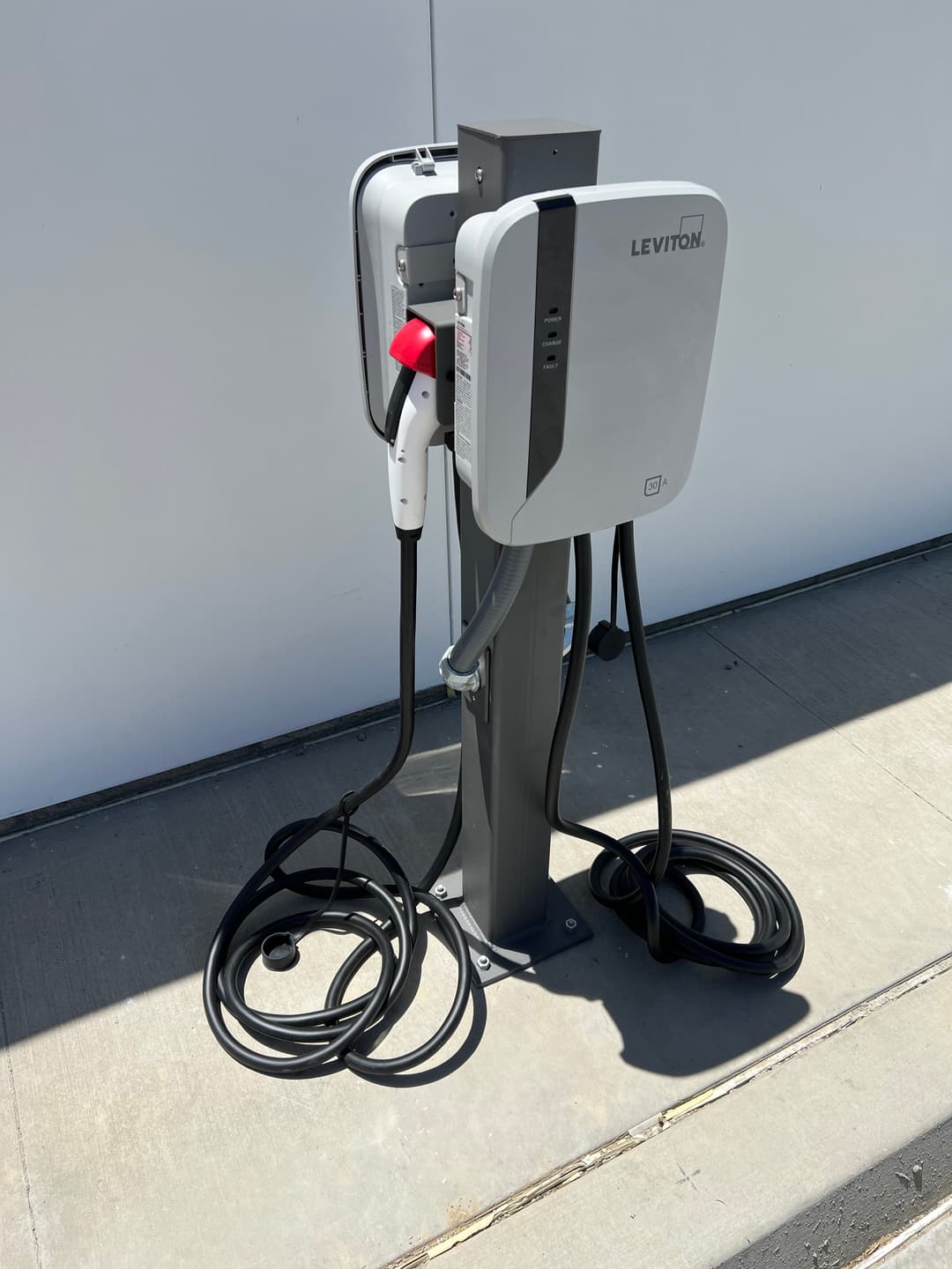 Leviton electric vehicle charging station with two charging cables mounted on a pedestal.