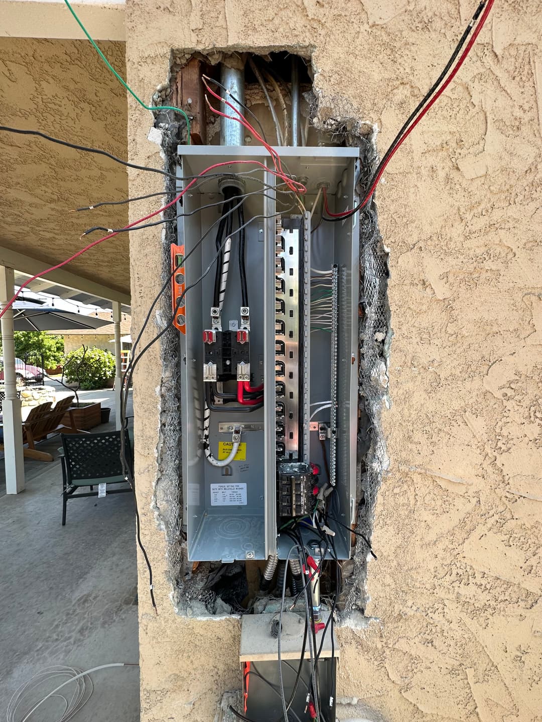 Open electrical panel installation with exposed wires on a textured wall.