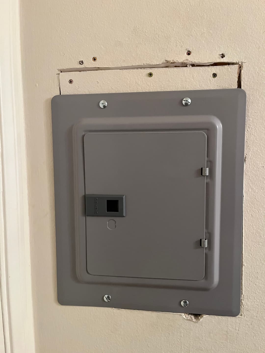 Electrical panel mounted on a wall, with visible installation marks around the edges.