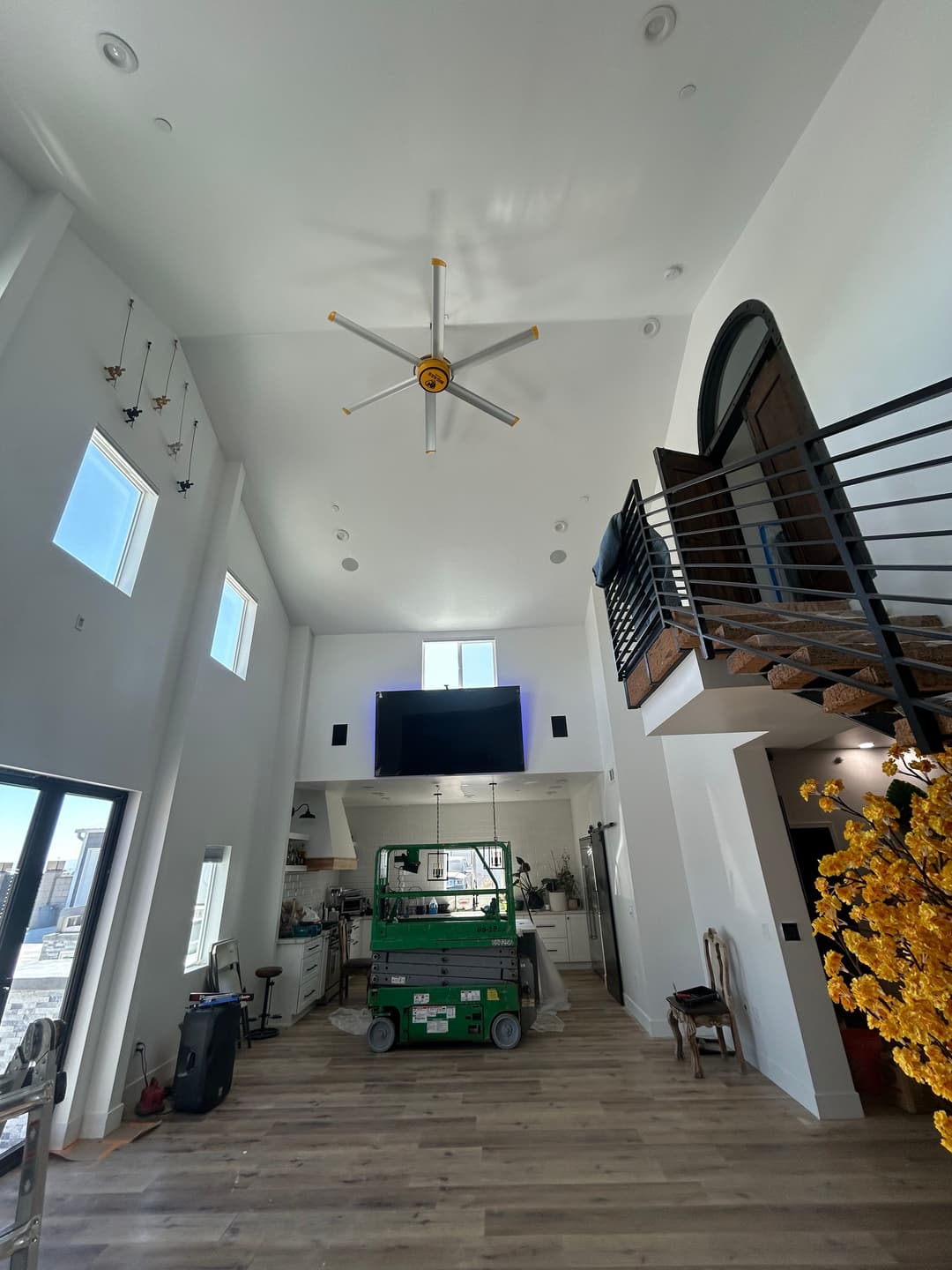 Spacious modern living room with high ceilings, large windows, and a construction lift.