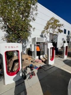 Tesla Supercharger station with charging units and equipment outside a building.