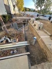 Construction site featuring pipes, tools, and equipment near a building.