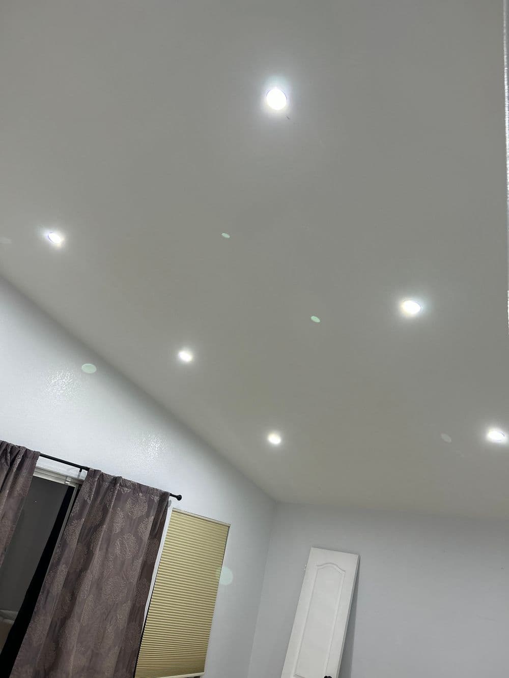 Ceiling with recessed LED lights and curtains in a modern room setting.