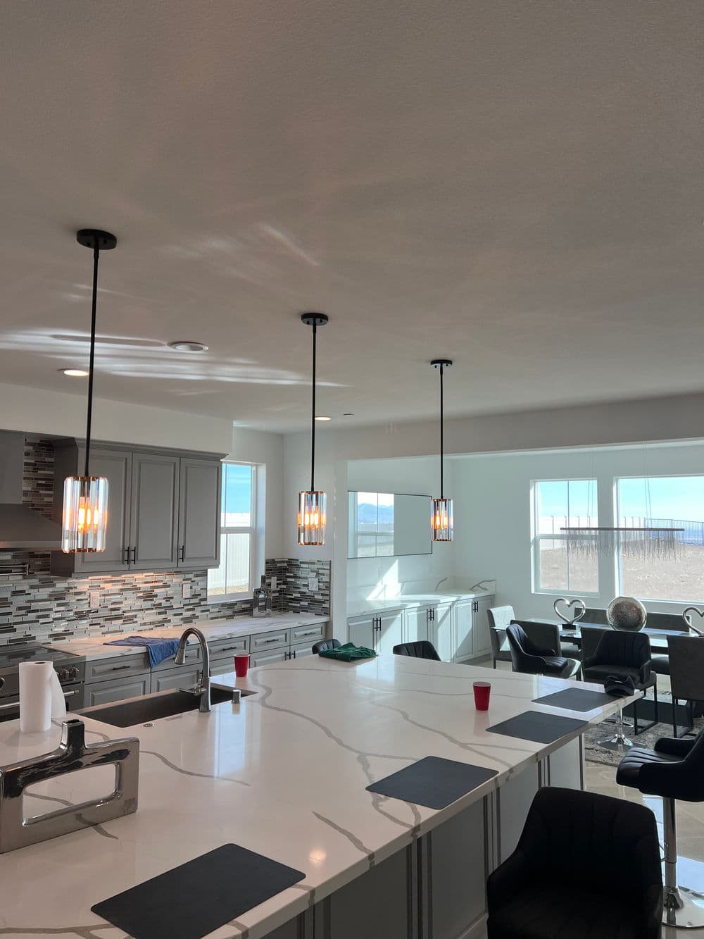 Modern kitchen with pendant lights, marble countertops, and sleek furniture. Mountain view windows.