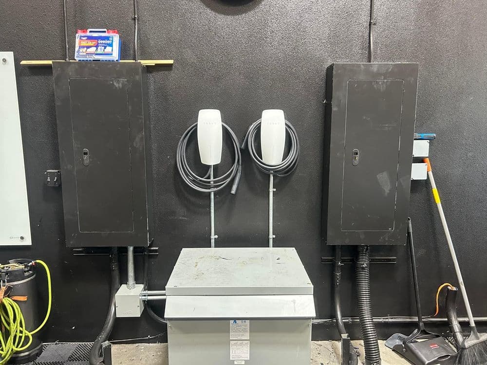 Electrical charging stations mounted on a wall with cable management and service panels.